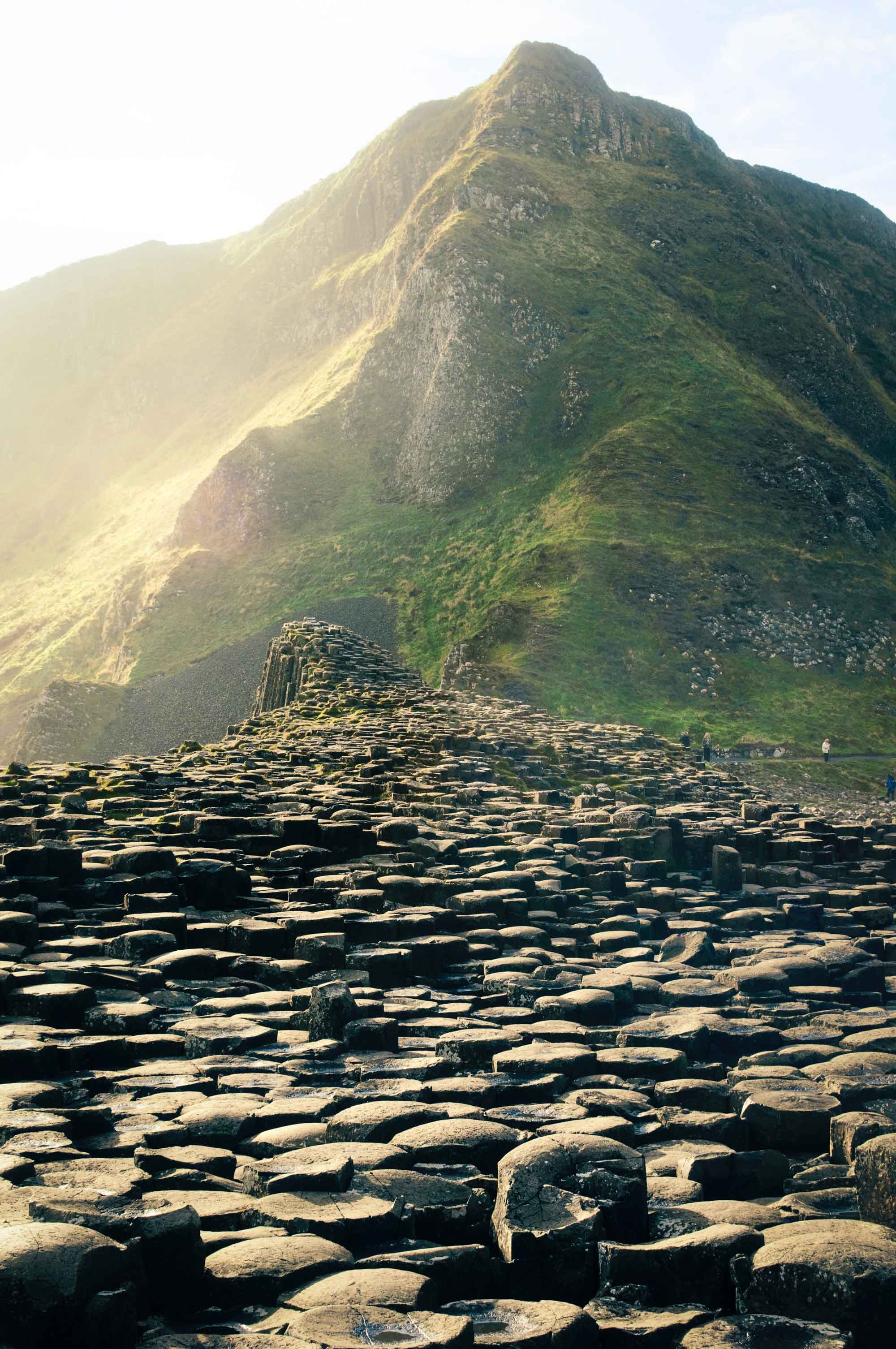 Irish green hills rising steeply above a field of uneven stones. SOMOS literary pilgrimages.