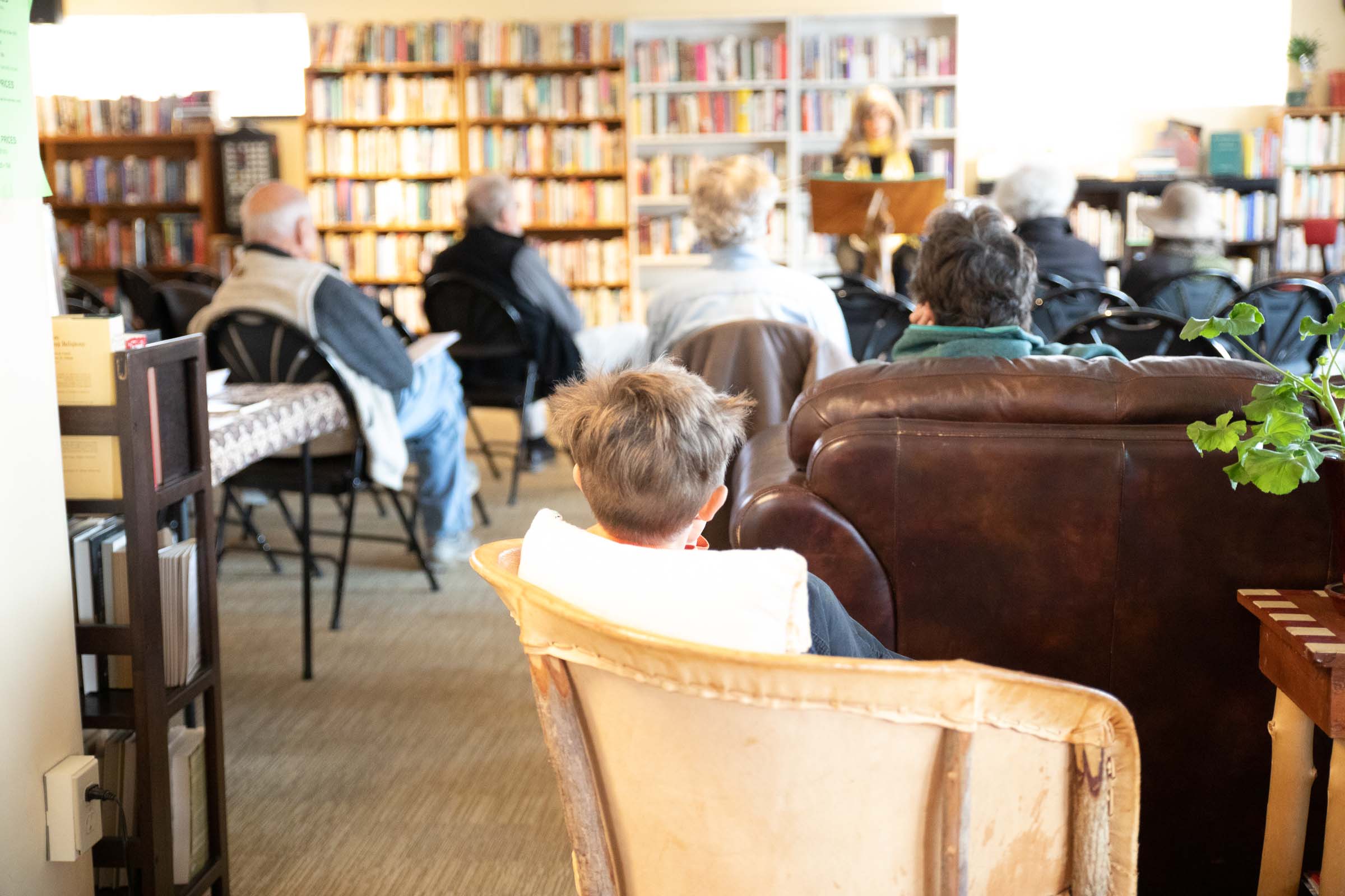 Young boy listening while a woman speaks to a group at SOMOS